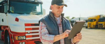 Man on tablet in front of a semi truck